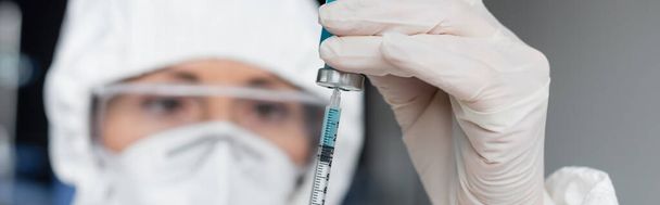 Fecskendő és vakcina homályos hátterű tudós kezében, banner  - Fotó, kép