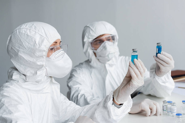 Scientist holding vaccine near colleague in laboratory  - Φωτογραφία, εικόνα