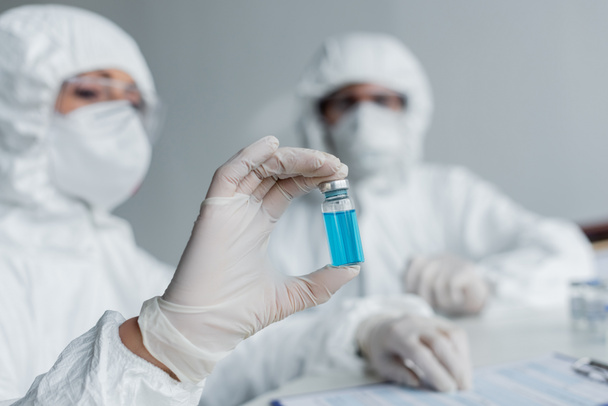 Vacuna en mano del científico que trabaja con su colega en laboratorio  - Foto, Imagen