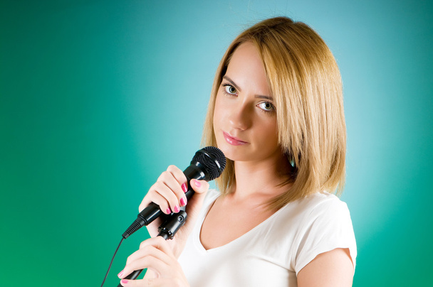 Girl singing with microphone against gradient background - Zdjęcie, obraz