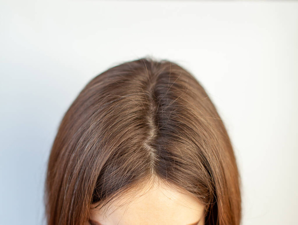 A cabeça de uma mulher com uma separação de cabelos grisalhos que cresceu raízes devido à quarentena. Cabelo castanho na cabeça de uma mulher close-up. - Foto, Imagem
