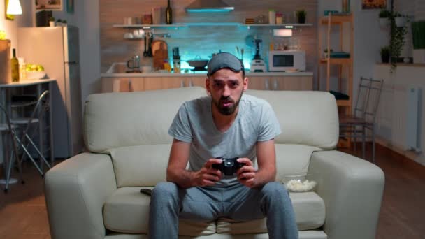 Un homme concentré tenant un joystick assis devant la télévision - Séquence, vidéo