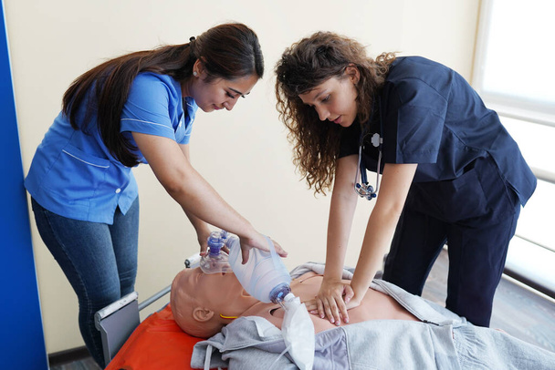 Los estudiantes de enfermería están aprendiendo a rescatar a los pacientes en situación de emergencia. Entrenamiento de RCP con muñeca de RCP. - Foto, imagen