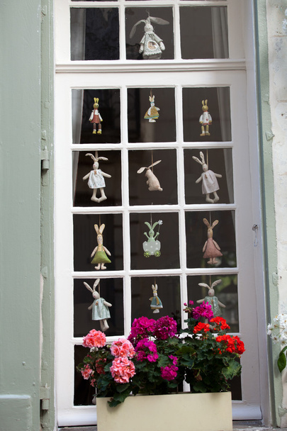 Белое окно с цветочным горшком и смешными висячими куклами
 - Фото, изображение