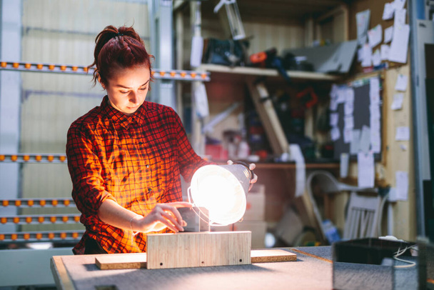 Vrouw gladder werker plakt glas ruiten met ultraviolette lamp. Industrie, handenarbeid - Foto, afbeelding