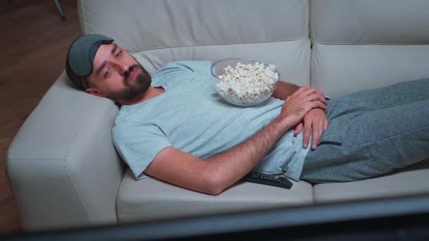 Hombre cansado tumbado en el sofá viendo el espectáculo de películas - Imágenes, Vídeo
