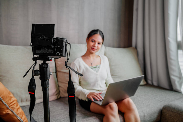 Азиатский блоггер, подкастер или блоггер смотрит в камеру и разговаривает на видео съемки с помощью технологий. Социальные медиа влияют на людей или контент создатель концепции в расслабляющий повседневный стиль дома - Фото, изображение