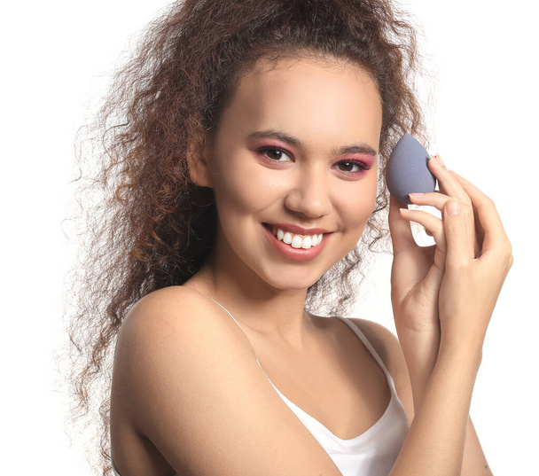 Beautiful young African-American woman with makeup sponge on white background - Photo, Image