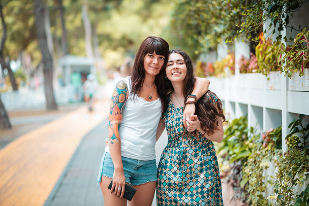 Summer vacation. Portrait of two young women embrace in the street. The concept of friendship and homosexual relationships. - Photo, Image