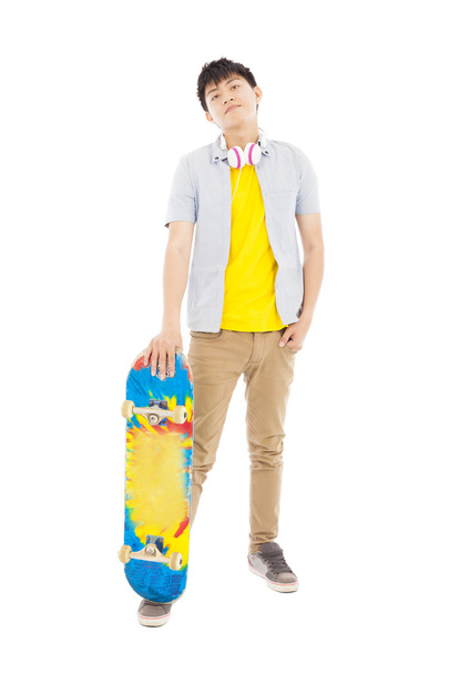 full length of a young man standing and holding a skateboard - Фото, зображення