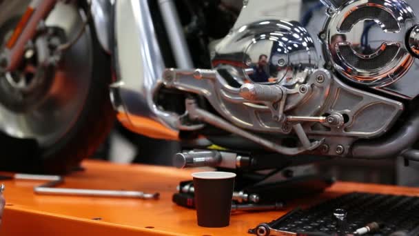 Mies sekoittaa kahvia jakoavaimella moottoripyörän lähellä työpajassa. - Materiaali, video