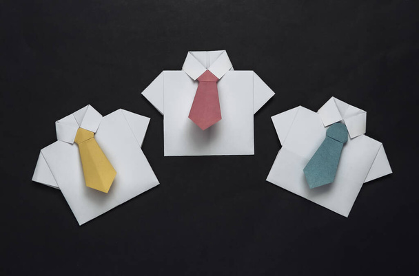 Camisas de origami con corbatas sobre fondo negro. Liderazgo, trabajo en equipo, concepto de negocio - Foto, imagen