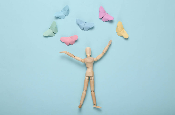 Wooden happy puppet and origami butterflies on a blue background - Photo, Image