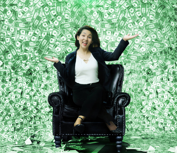 百万のようなお金でいっぱいの椅子に座っている幸せなアジアの女性宝くじやビジネスの報酬を獲得から - 写真・画像
