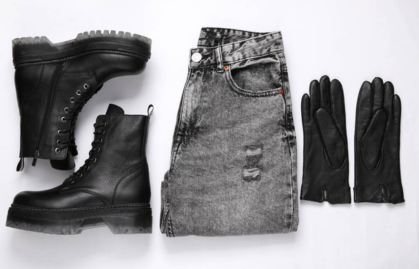 Dameskleding en accessoires. Jeans en lederen zwarte laarzen, handschoenen op een witte achtergrond. Bovenaanzicht - Foto, afbeelding