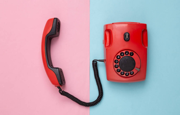 Retro czerwony staromodny telefon obrotowy na różowym niebieskim tle. Widok z góry - Zdjęcie, obraz