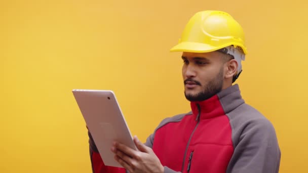 Junger Ingenieur mit gelbem Helm mit Tablet. Isoliert - Filmmaterial, Video