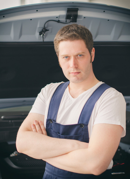 Young handsome mechanic standing near open car hood - Φωτογραφία, εικόνα