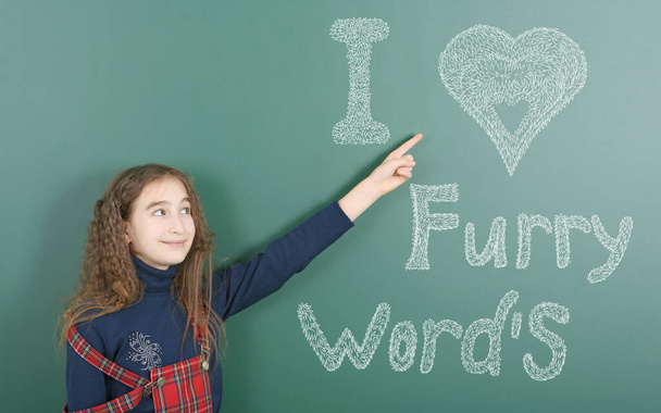 Pre-adolescent meisje wijst met de vinger naar pluizig opschrift "I love furry word 's". Hoge resolutie foto. Volledige velddiepte. - Foto, afbeelding