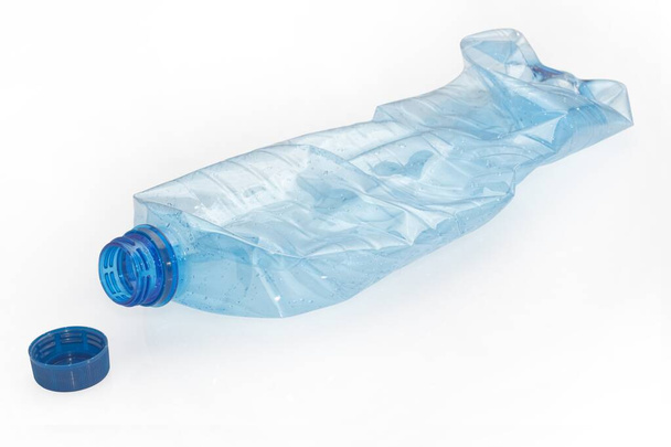 garrafa de plástico esmagado e tampa de rosca no fundo branco - Foto, Imagem