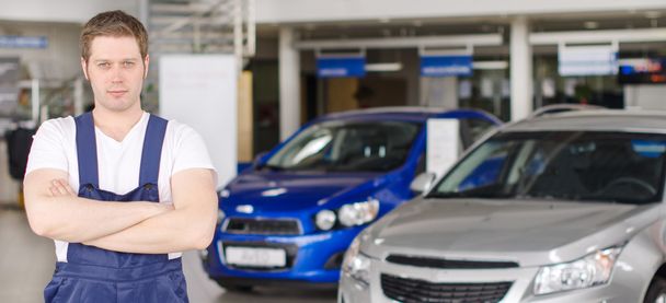 Young handsome mechanic in car dealership. Place for text. - Photo, Image