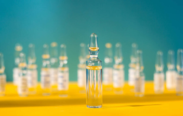 Muchas ampollas con fondo amarillo-azul de la vacuna (como la bandera de Ucrania). Concepto de medicina - Foto, imagen
