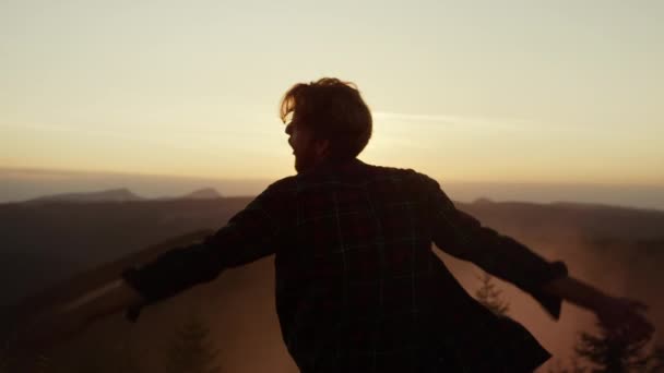Мужчина танцует в горах на закате. Счастливчик жестикулирует руками во время танцев - Кадры, видео