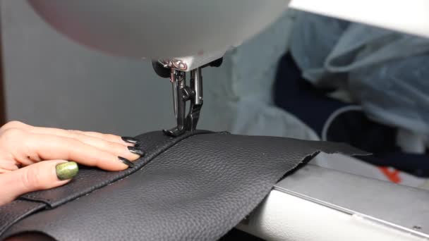 Máquina de coser de cuero en acción en un taller con las manos trabajando en un bolso de hombro - Imágenes, Vídeo