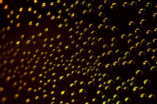 Air bubbles in the water. Metallic bubbles in a glass of water. Soda water in close-up, on dark background. - Photo, Image