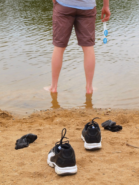 Turuncu kum Gölü banka üzerinde siyah beyaz koşu ayakkabıları. su seviyesi, sağ elinde su zekâ ve yüzme gözlüklü adam şekil üzerinde bulanık dalgalar. - Fotoğraf, Görsel
