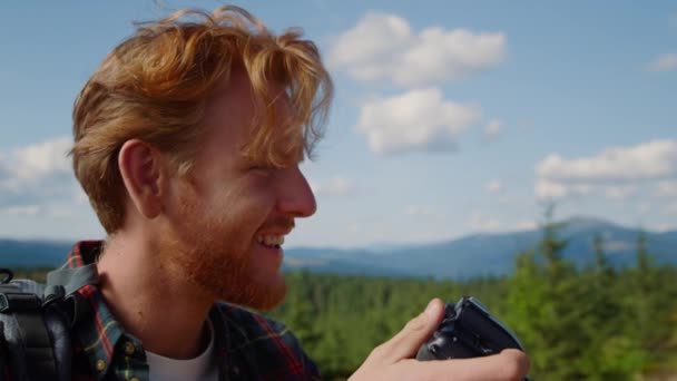 Улыбающийся парень фотографирует живописный пейзаж на профессиональную камеру - Кадры, видео
