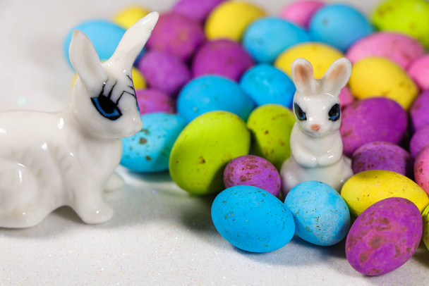 Coniglietti con uova di caramella maculate su bianco nevoso - Foto, immagini