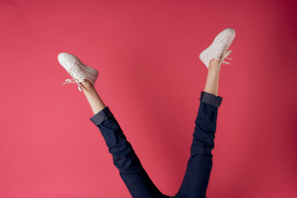 Inverted female legs white sneakers motion street style pink background - Fotó, kép