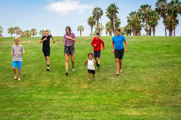 Gran grupo diverso de niños activos corriendo juntos en un parque al aire libre. Niños y niñas de diferentes edades se divierten jugando juntos al aire libre - Foto, Imagen