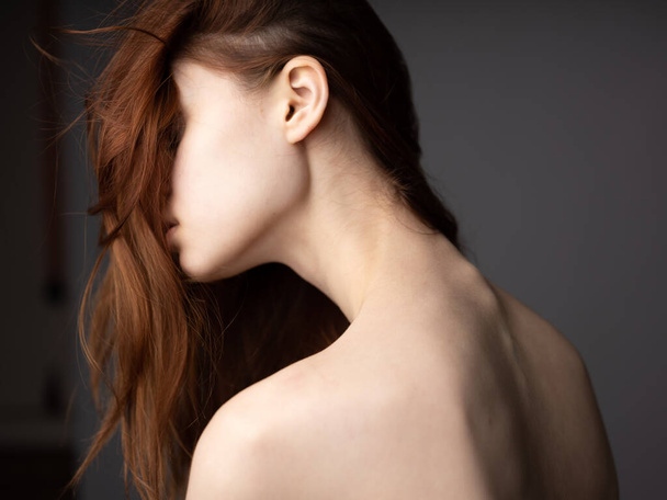 Сексуальная женщина с обнаженной спиной на сером фоне с рыжими волосами - Фото, изображение