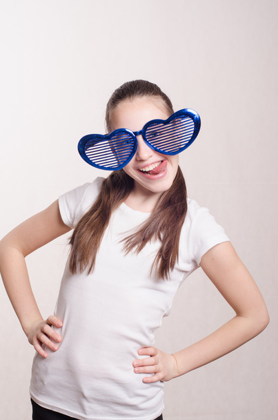 Смішна маленька дівчинка у великих окулярах показує язик
 - Фото, зображення