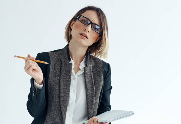Uma mulher com um caderno e uma caneta em suas mãos em um terno financeiro de negócios de fundo leve - Foto, Imagem