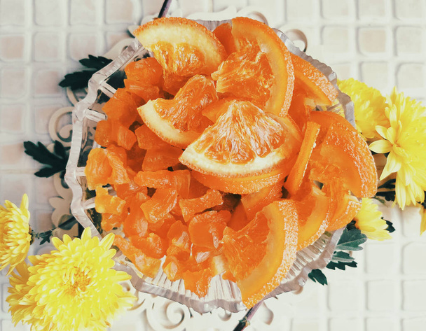 ζαχαρωμένες φέτες πορτοκαλιού, διακόσμηση φρούτων και κίτρινα χρυσάνθεμα - Φωτογραφία, εικόνα
