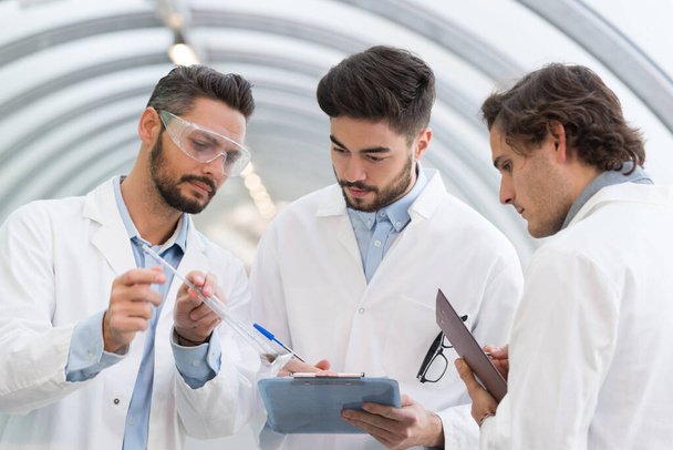 three men in labcoats in discussion - Photo, image
