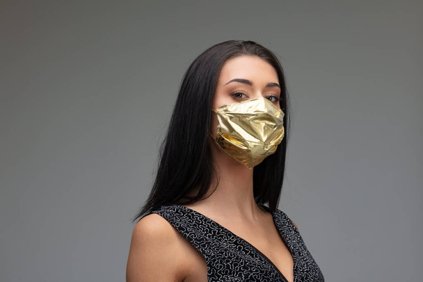 ylimielinen nainen yllään kultainen kasvonaamio käsite kirurgiset naamarit hinnannousu, kun ne ovat pakollisia ja erittäin harvinaisia, koska niitä tarvitaan lieventämään COVID19 viruksen pandemia leviämistä - Valokuva, kuva