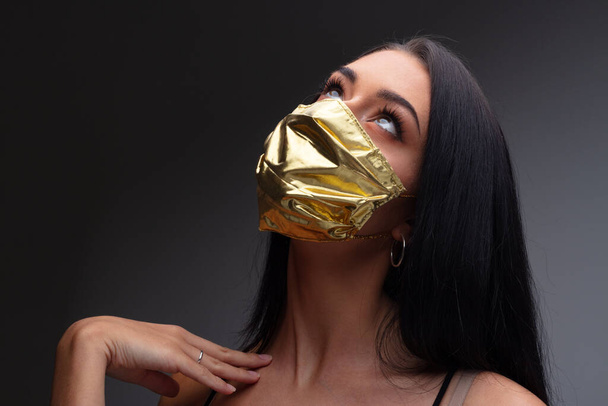 aumento de preços de máscaras faciais e escassez em COVID-19 vezes conceito como uma bela menina jovem se gabando e ostentando sua máscara facial feita de ouro, porque ela pode pagá-lo, mesmo que eles se tornem um extremamente raro bom - Foto, Imagem