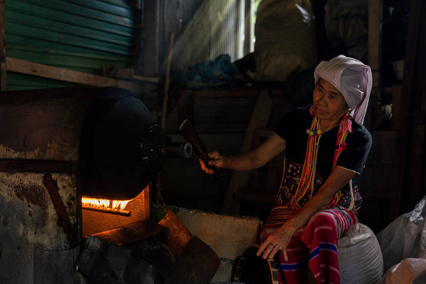 Горянка, що смажить каву. Горбаті жінки сортують кавові зерна. Стара жінка вибирає смажену кавову бобу. Таїланд. - Фото, зображення