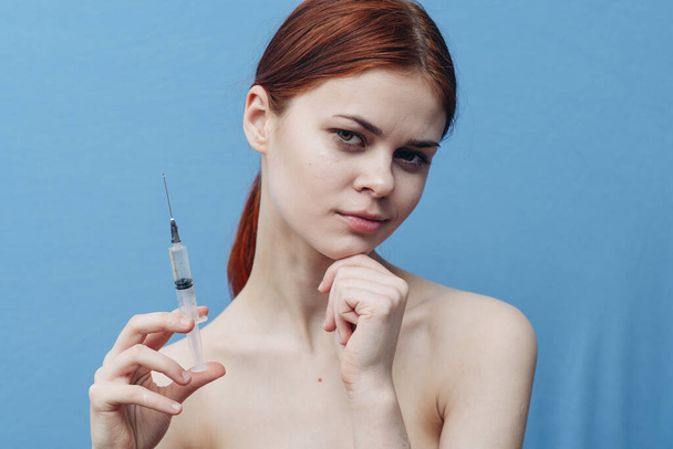 seringa na mão mulher em azul fundo injeção rejuvenescimento botox corte vista - Foto, Imagem