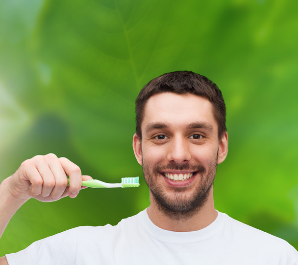 Smiling young man with toothbrush - Foto, afbeelding