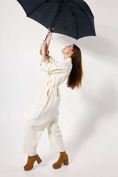 Женщина в белом комбинезоне с открытой зонтичной защитой от дождя - Фото, изображение