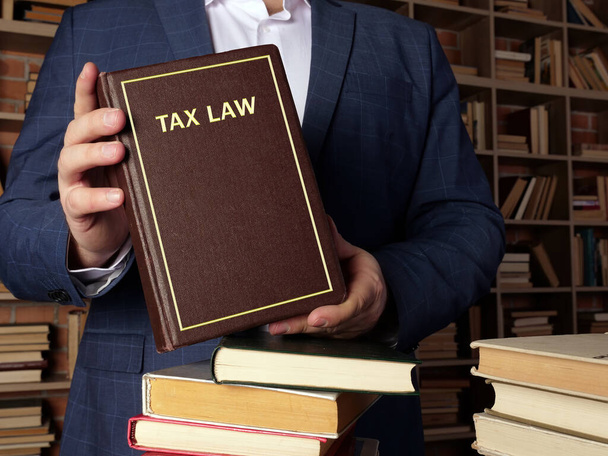  本には税法の文言がある。それは、財産、取引、財産、収入、ライセンスおよびモルに関する費用を含む税務プロセスを監督する規則、ポリシーおよび法律をカバーしています。 - 写真・画像