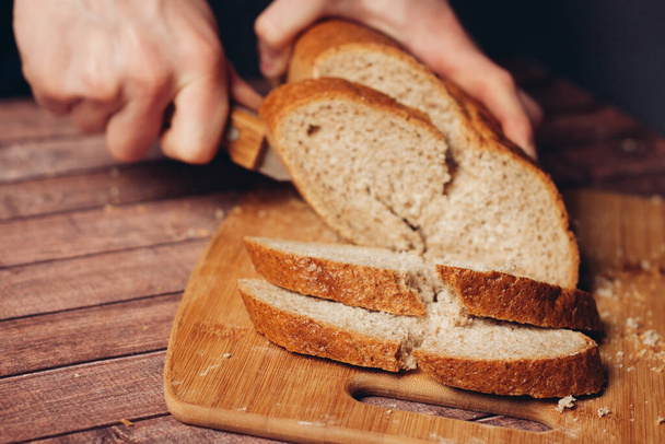 slicing fresh bread on a wooden cutting board breakfast  - Foto, Imagem