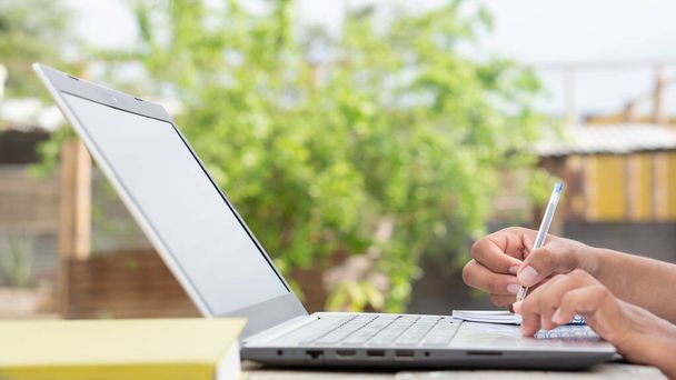 Manos latinas usando una computadora. Dedos marrones tocando un portátil. Laptop touchpad siendo utilizado por manos latinas. Estudiar al aire libre. - Foto, imagen