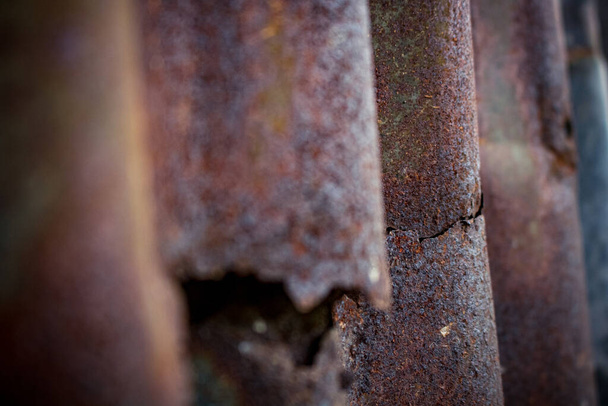 Damaged galvanized iron sheet wall on old warehouse. Detail view of old rusty corrugated metal sheet. - Photo, Image