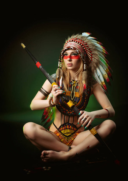 kobieta na obraz amerykańskiego Indianina w karaluchowym nakryciu głowy na ciemnym tle - Zdjęcie, obraz
